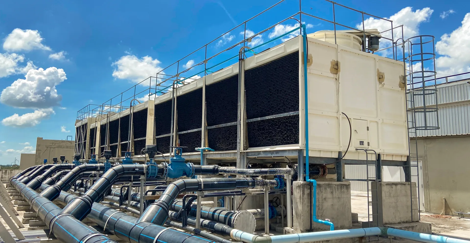 Industrial cooling towers with pipework against a blue sky