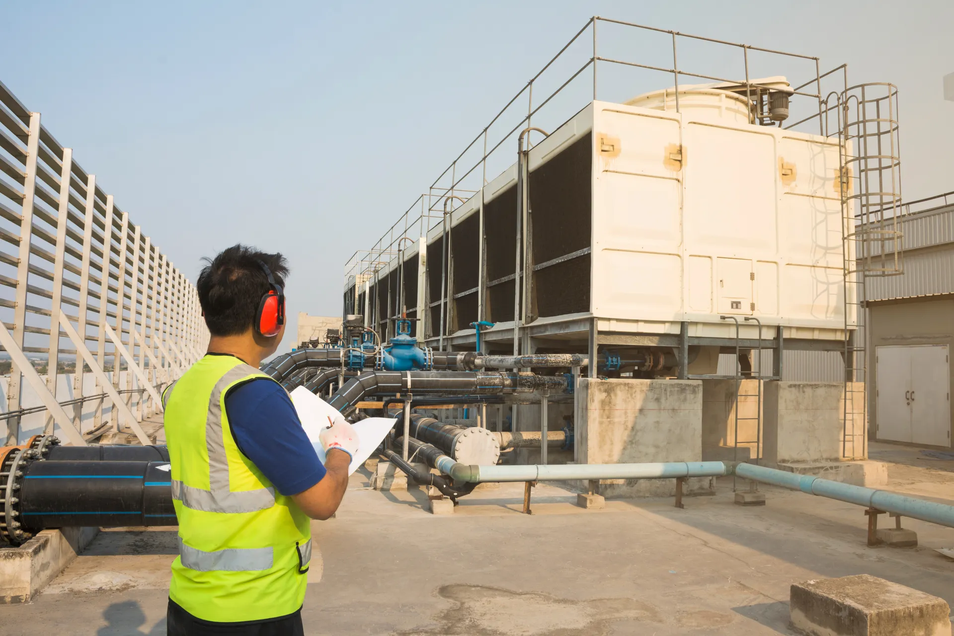 Engineer with clipboard inspecting a cooling tower installation