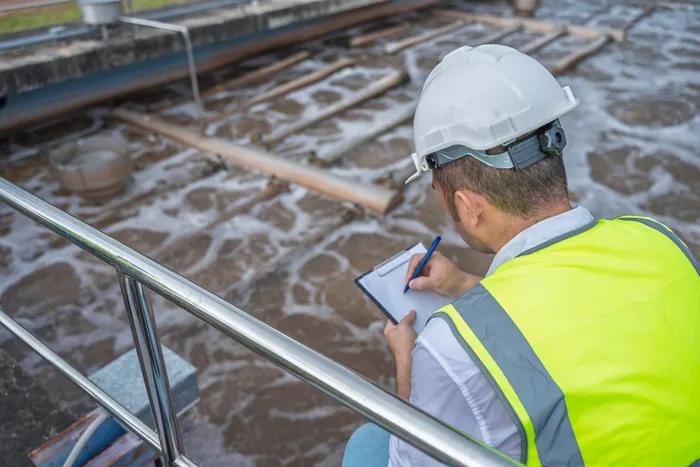 Engineer sampling water at a wastewater aeration basin