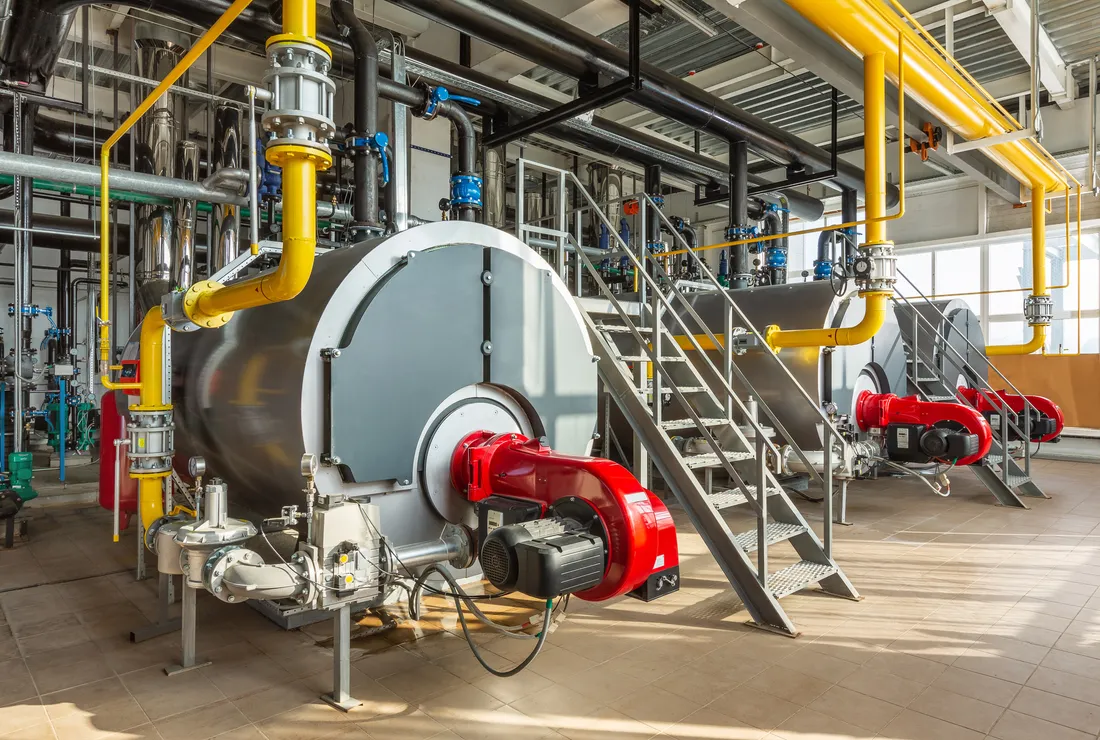 Industrial gas-fired boilers with burners and pipework in a plant room