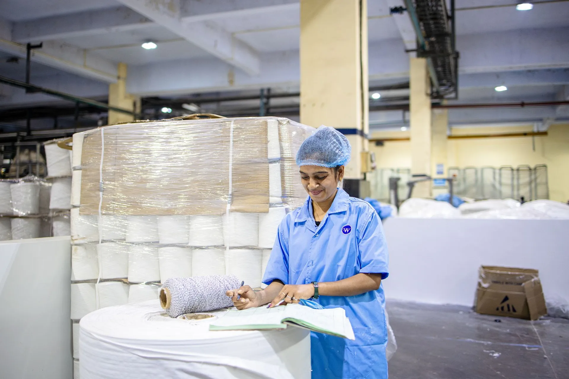 Mill floor with large paper reels and a quality inspector