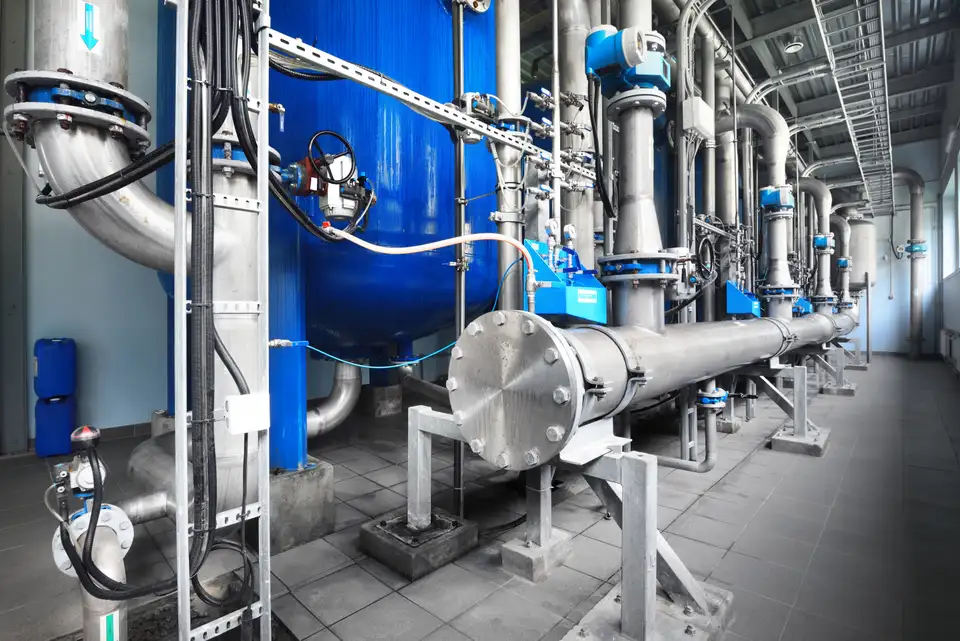 Industrial pump room with blue pressure vessels and stainless-steel pipework