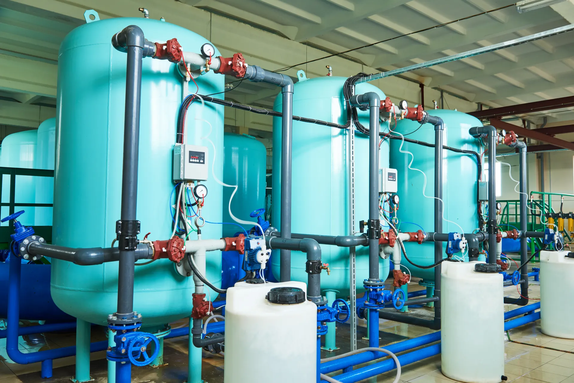 Teal water treatment vessels with dosing tanks in an industrial plant